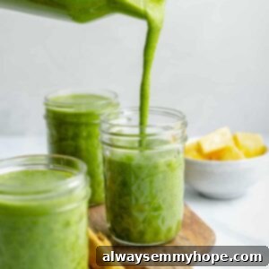 Simple Four Ingredient Green Smoothie 2 Green smoothie being poured into a mason jar, surrounded by two other jars of smoothies.