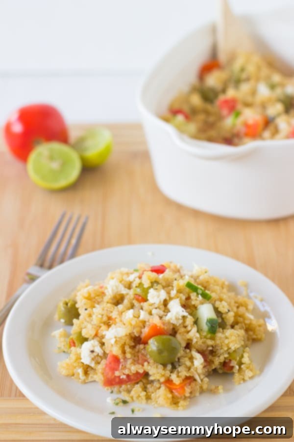 Top-down view of Mediterranean Quinoa Salad bowl on a wooden table, garnished with fresh herbs