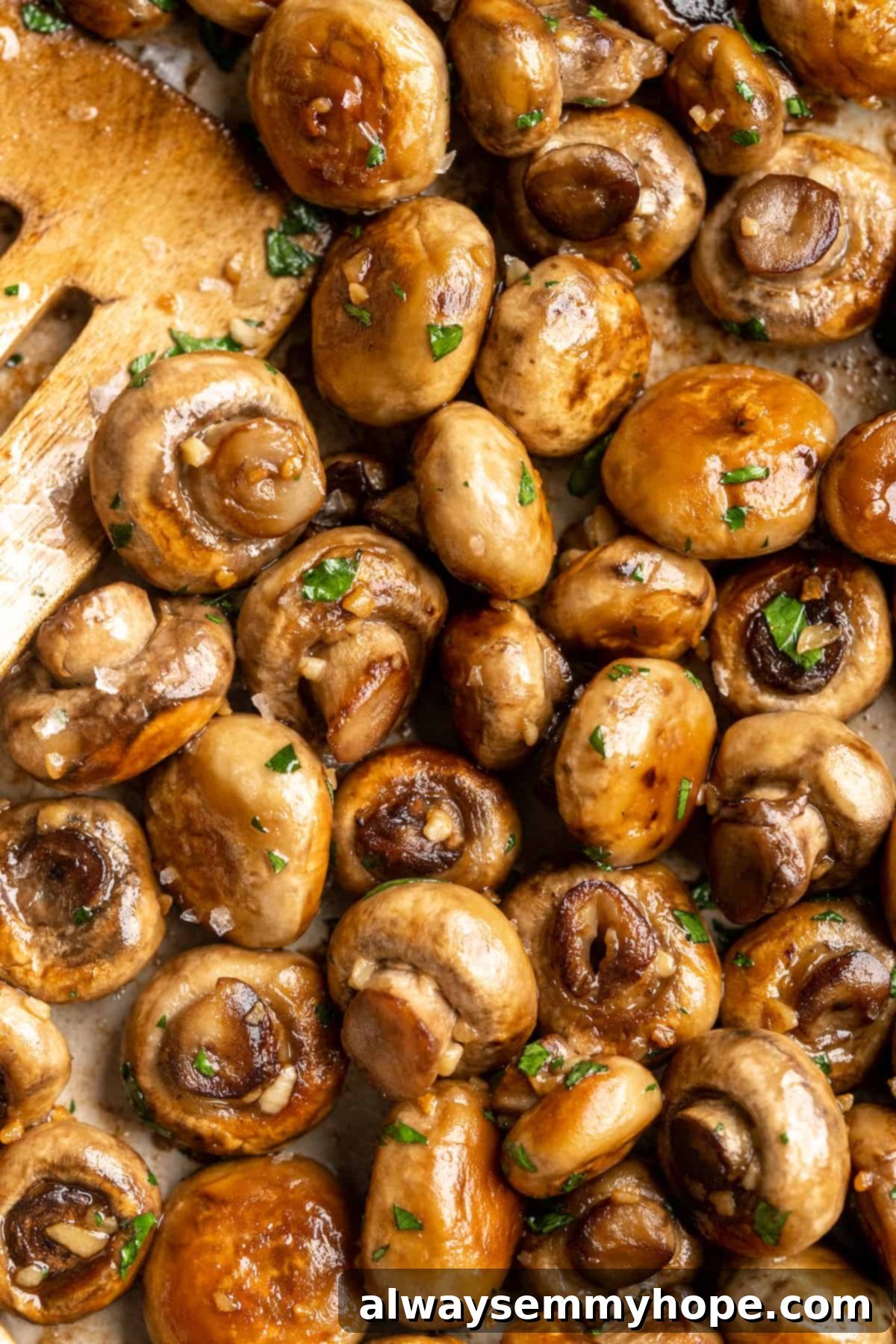 Garlic mushrooms in skillet with wooden spatula