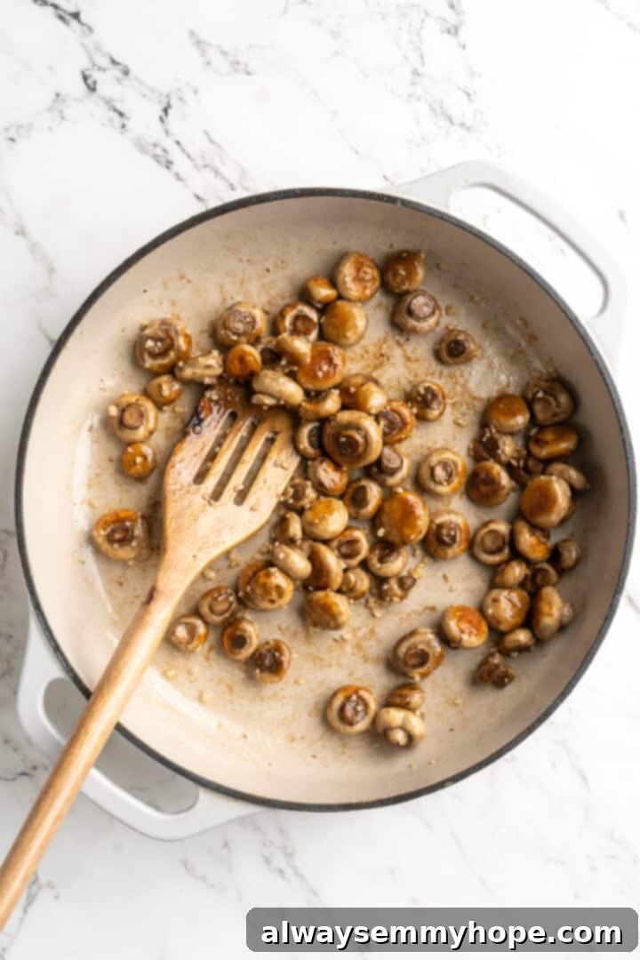 Overhead view of mushrooms browning in skillet with garlic