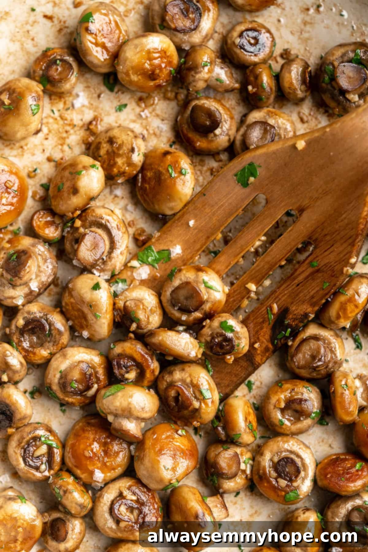Garlic mushrooms in skillet with wooden spatula