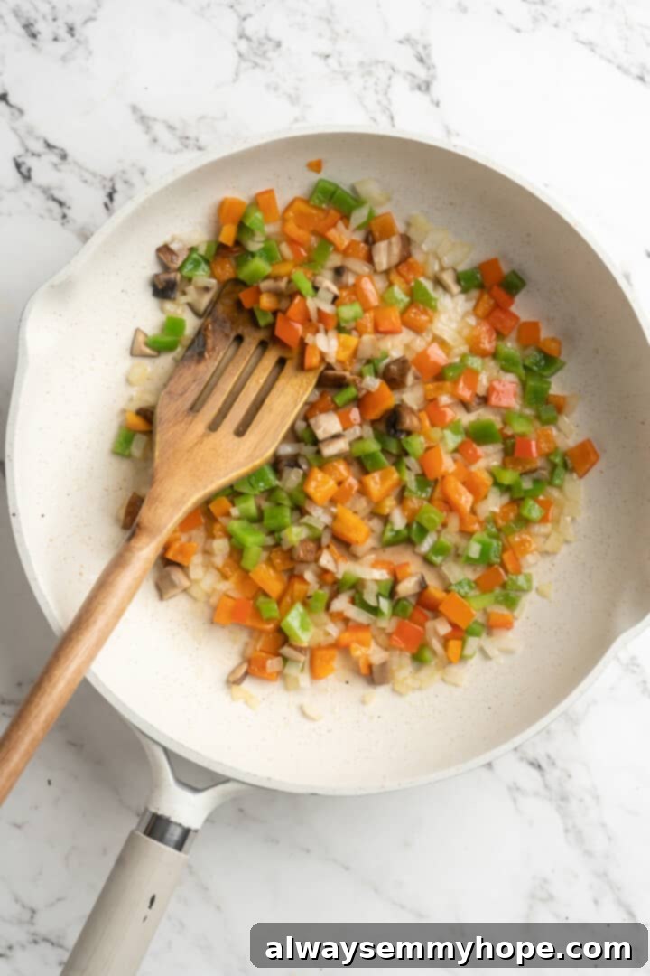 Overhead view of sautéed onions, bell peppers, and mushrooms in a skillet