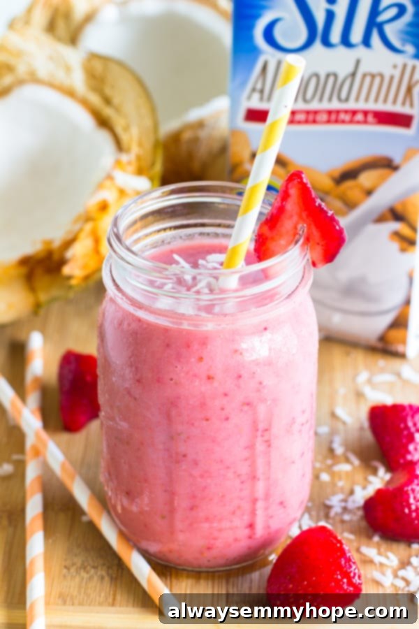 Strawberry coconut smoothie in a glass with a yellow straw.