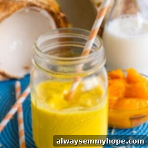Side shot of a vibrant mango coconut smoothie in a glass with a golden straw, ready to be enjoyed.