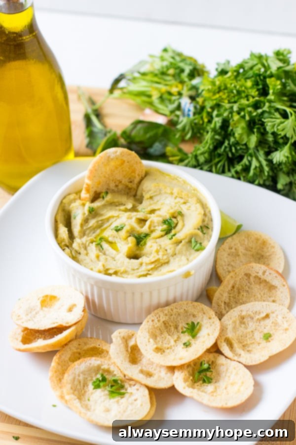 Herbed roasted garlic white bean dip in a white ramekin with chips, ready to be served as a delightful appetizer.