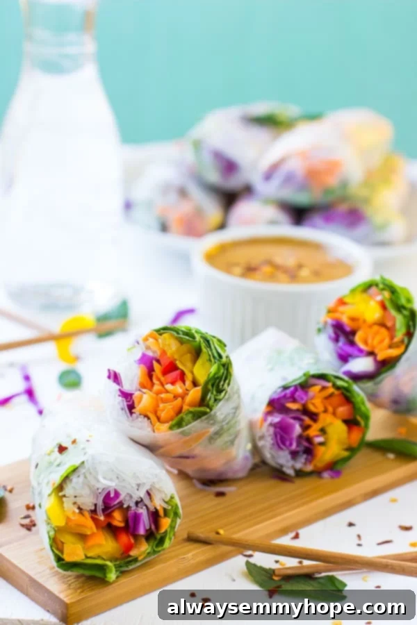 Four beautifully arranged fresh summer rolls on a rustic wooden board, with a stack of additional rolls and a bowl of dipping sauce blurred in the background, showcasing their vibrant colors and appealing presentation.