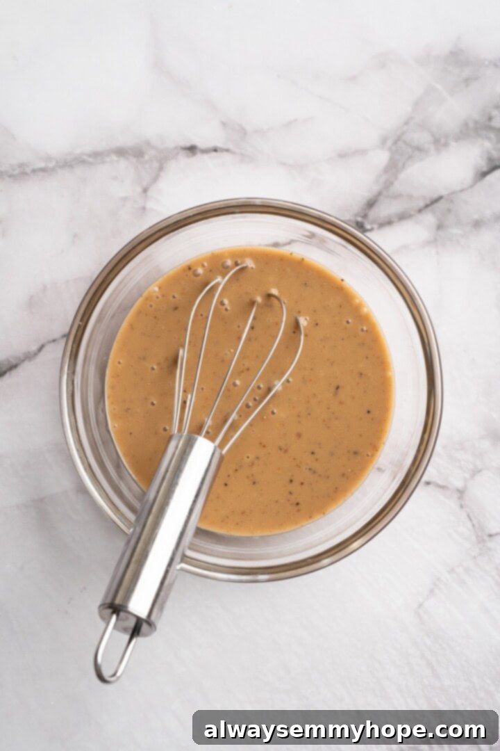 This beet feta salad pairs tender roasted beets and tangy vegan feta, along with a zippy maple mustard vinaigrette. Delicious and easy! Overhead view of maple mustard vinaigrette in bowl with whisk