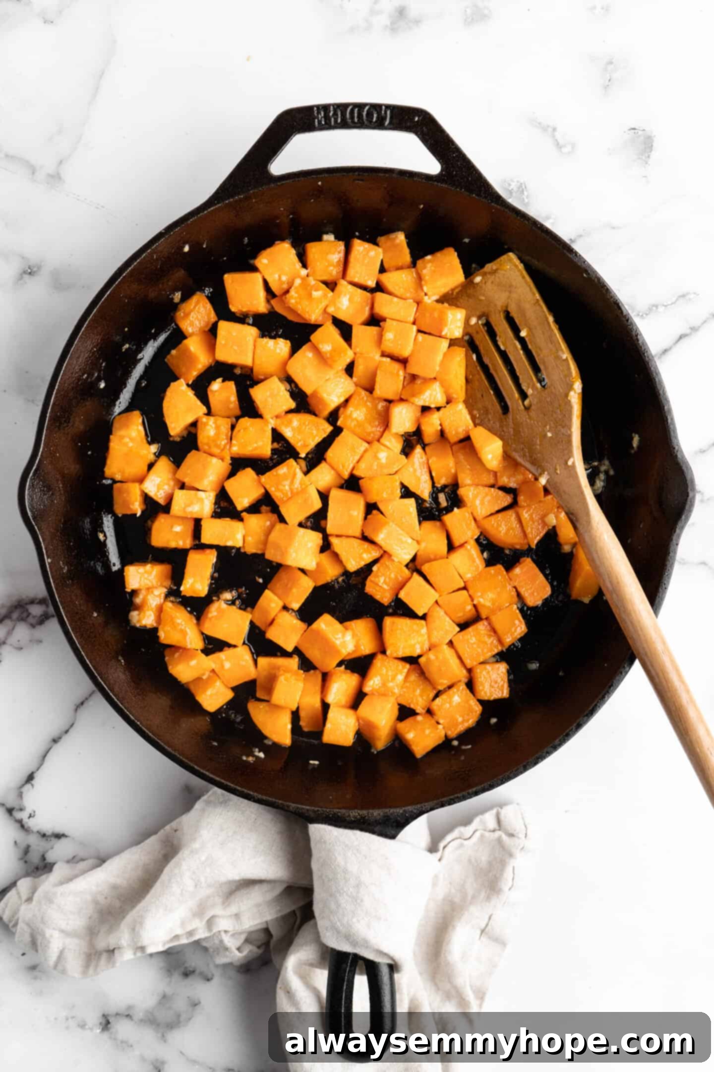 Close-up overhead view of diced sweet potatoes sautéing in a skillet, gently browning and releasing their natural sugars.