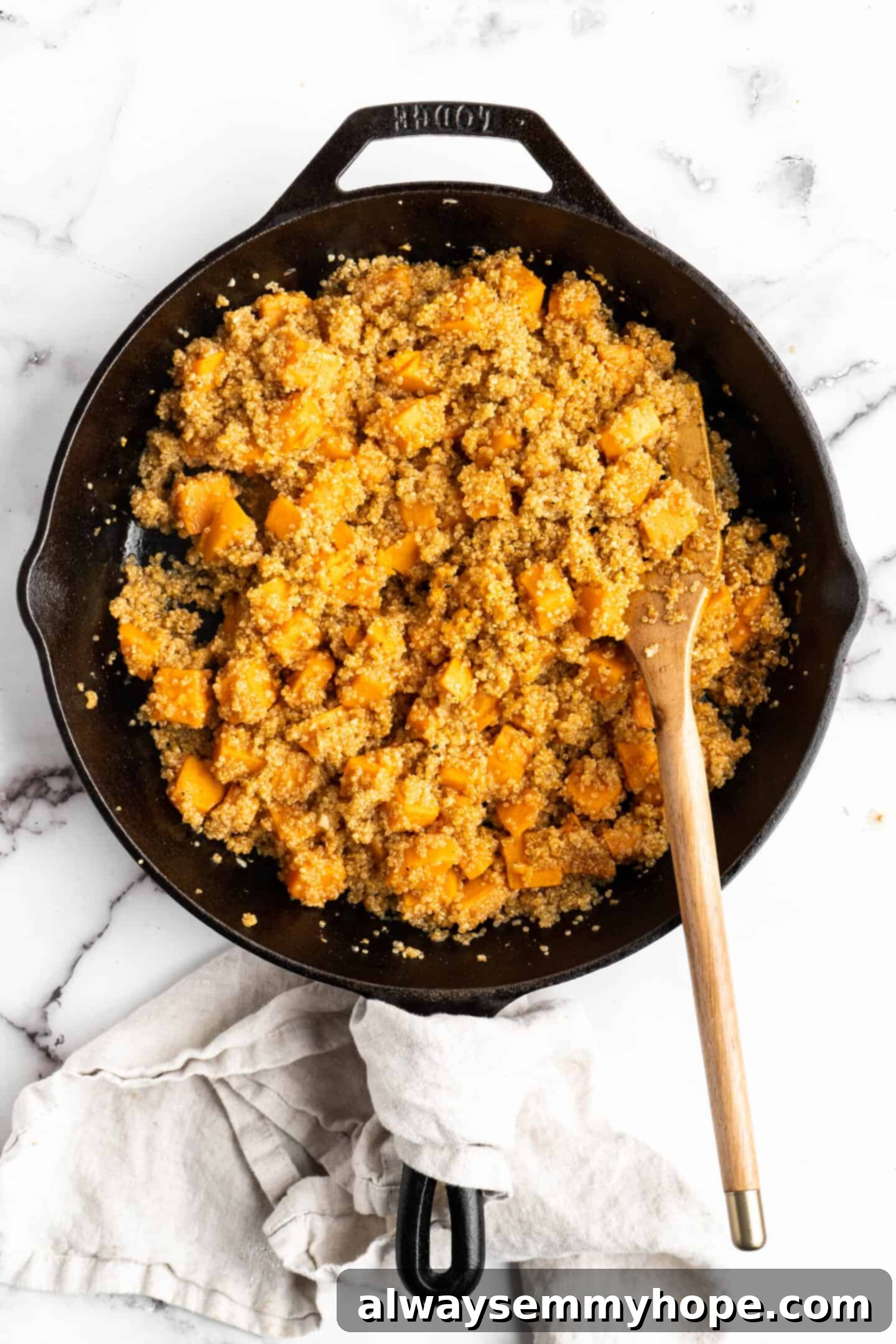 Fully cooked and fluffy quinoa mixed with tender sweet potatoes in a skillet, having absorbed most of the liquid.