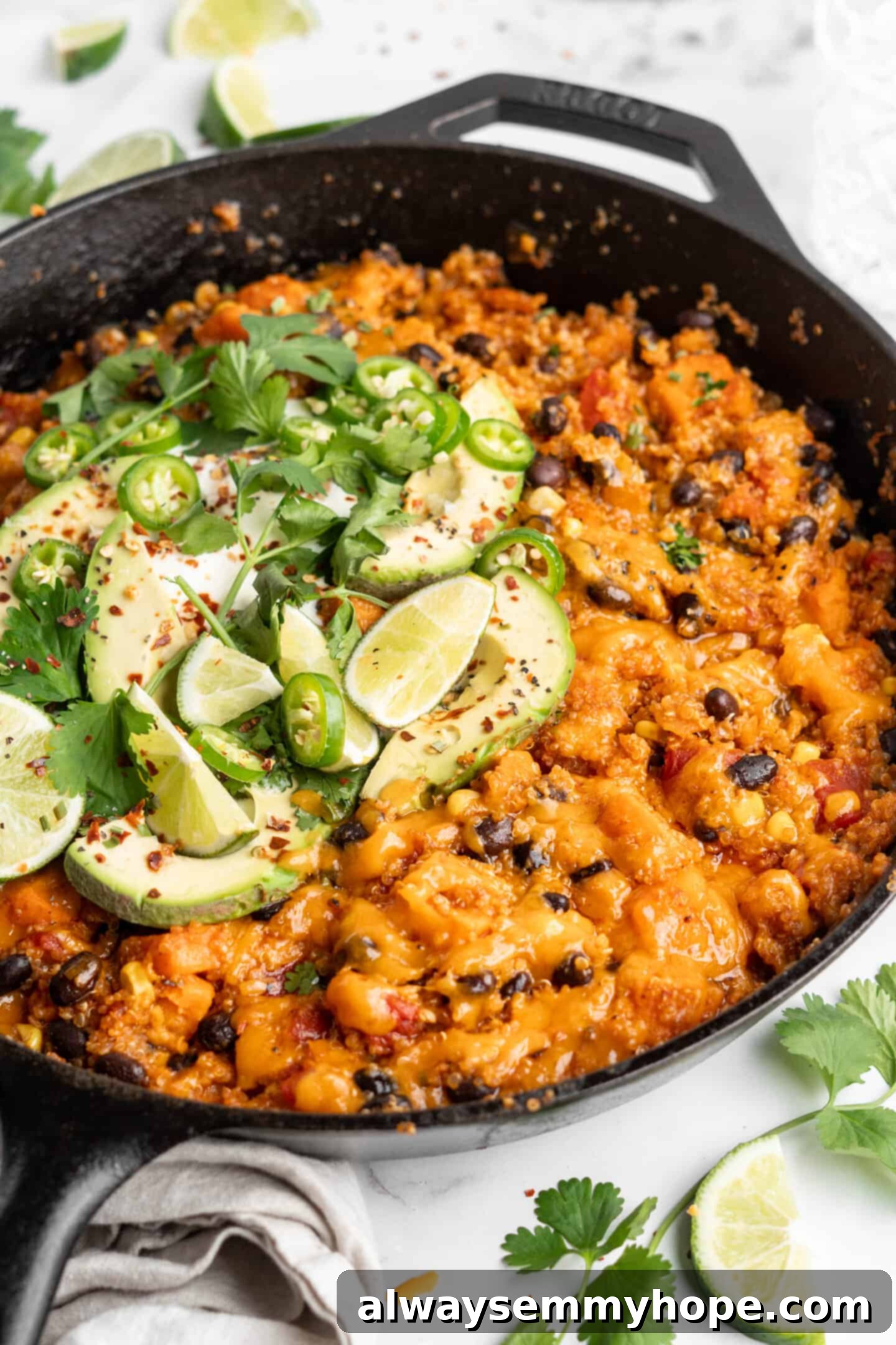 Close-up overhead view of the vegan enchilada skillet, showcasing the melted cheese and fresh green garnishes.