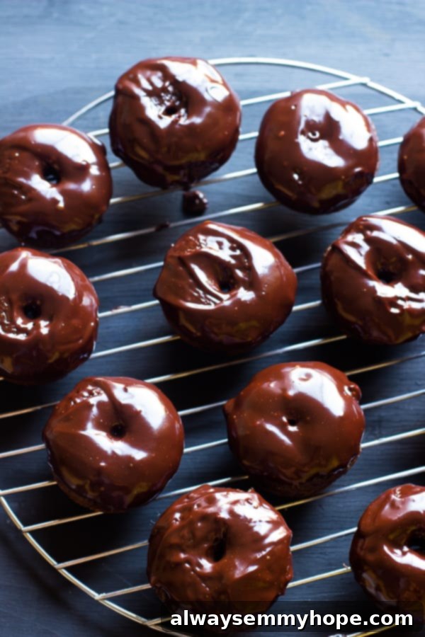 A top-down shot of several chocolate donuts cooling on a wire rack, showcasing their perfectly glazed tops.