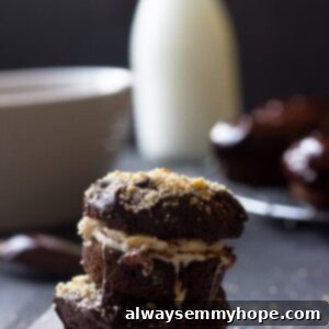 Side shot of chocolate donuts stacked on a table, with a rich chocolate glaze dripping down.