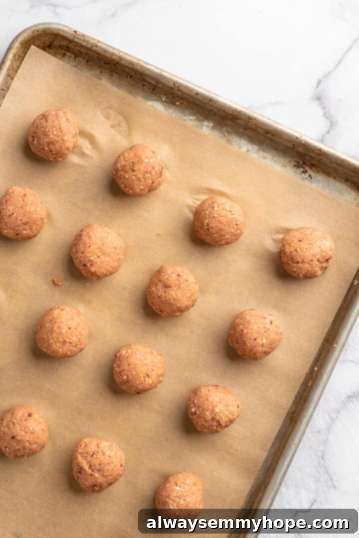 If you like your vegetarian meatballs with beans, veggies and BIG flavor, these chickpea and beet meatballs are for you. Great for meal prep! Overview of uniformly shaped unbaked chickpea and beet vegetarian meatballs arranged on a parchment-lined sheet pan, ready for baking.