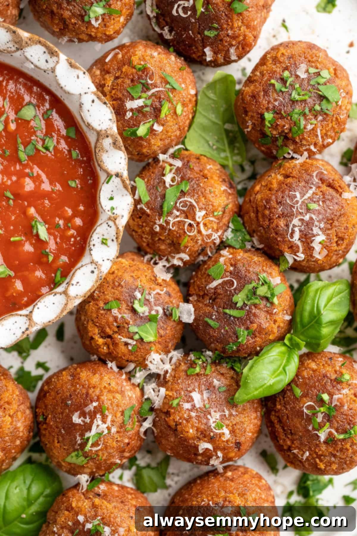 If you like your vegetarian meatballs with beans, veggies and BIG flavor, these chickpea and beet meatballs are for you. Great for meal prep! Overhead view of golden-brown chickpea and beet vegetarian meatballs artfully arranged on a platter, with a small bowl of marinara sauce beside them.