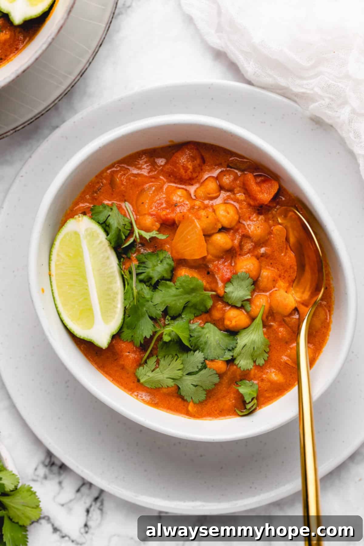 A close-up shot of creamy vegan coconut chickpea curry in a bowl, garnished with fresh cilantro.
