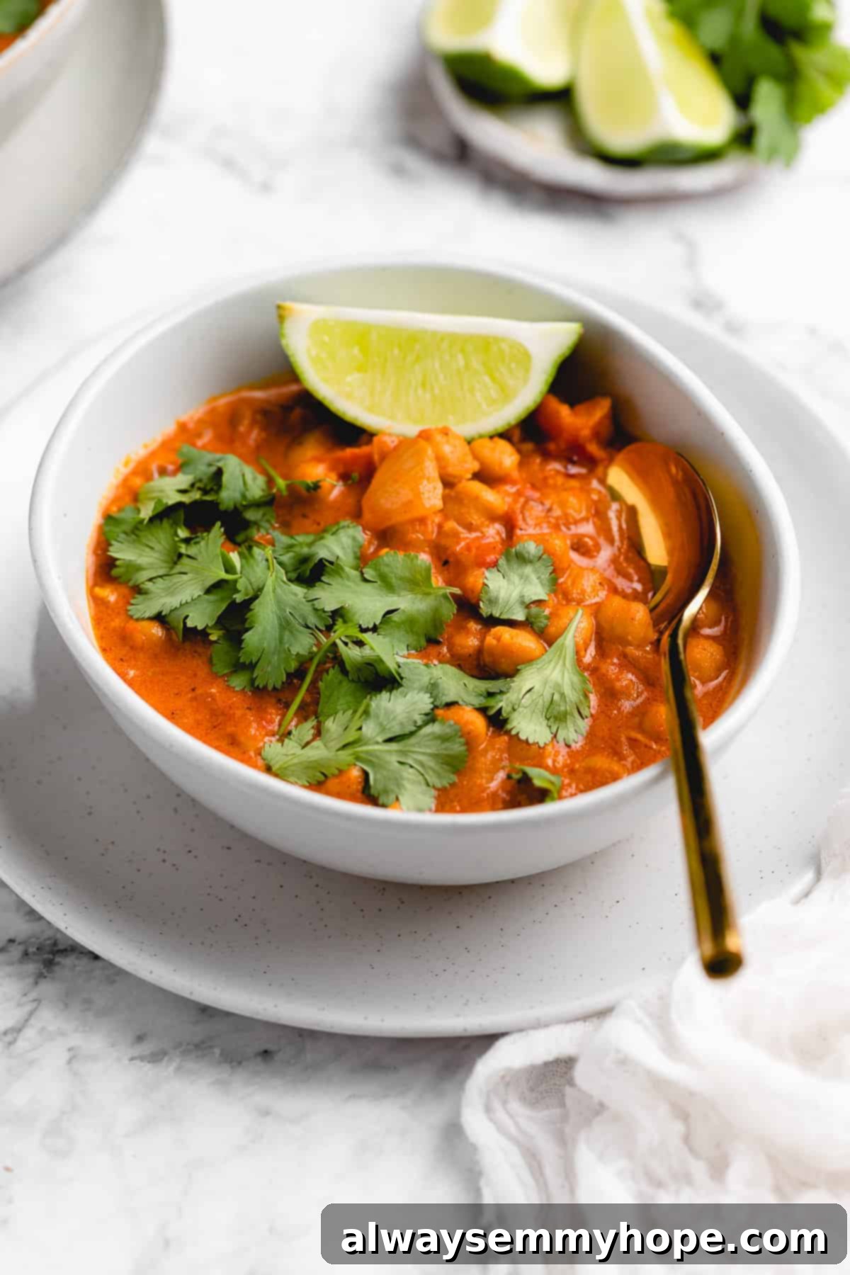 A bowl of creamy vegan coconut chickpea curry with rice and a spoon, ready to be eaten.