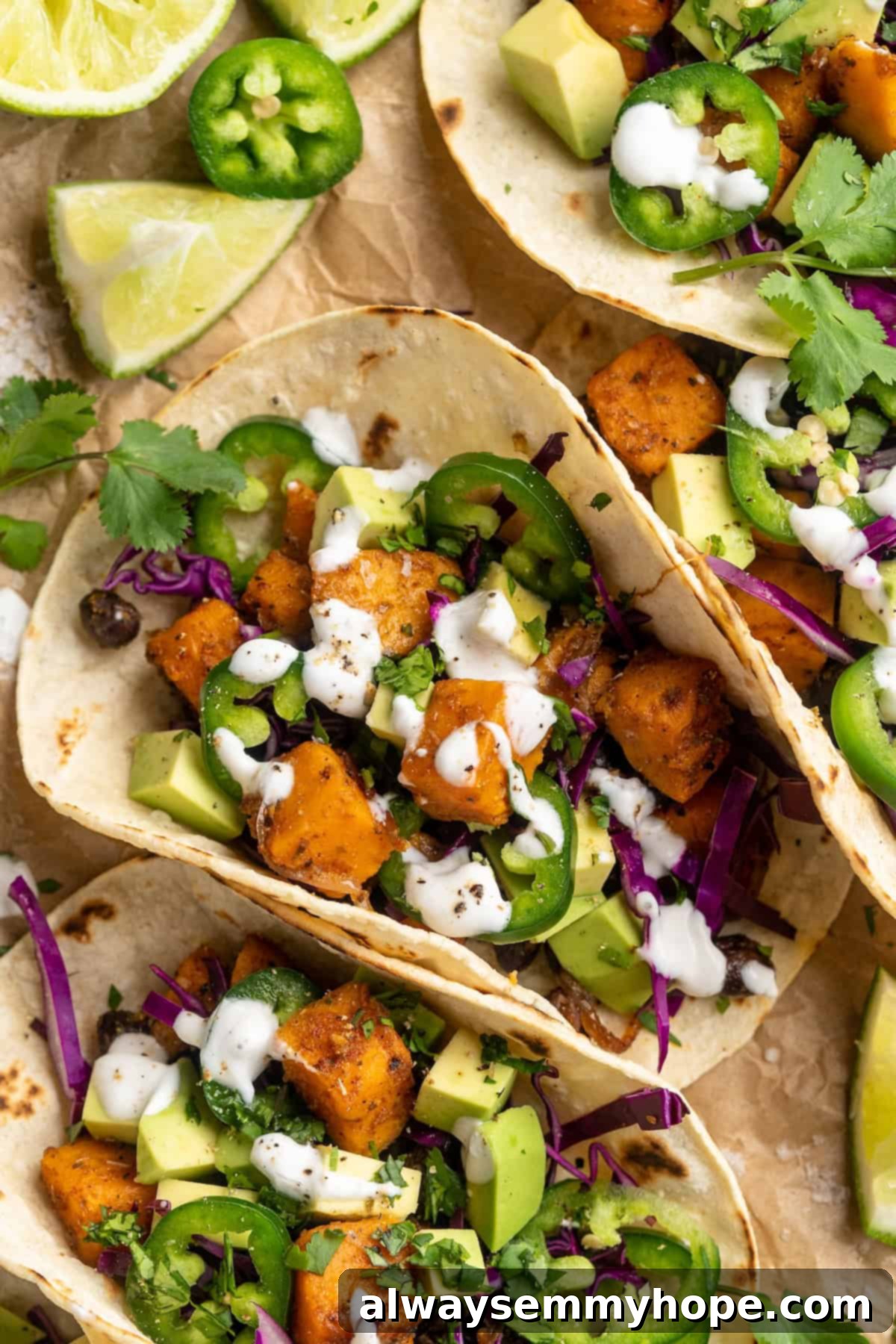 Overhead view of sweet potato and black bean tacos arranged on a platter, garnished with lime crema and fresh herbs, ready to be served