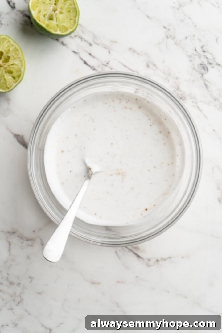 Overhead view of lime crema in a small bowl with a spoon, highlighting its smooth and creamy texture
