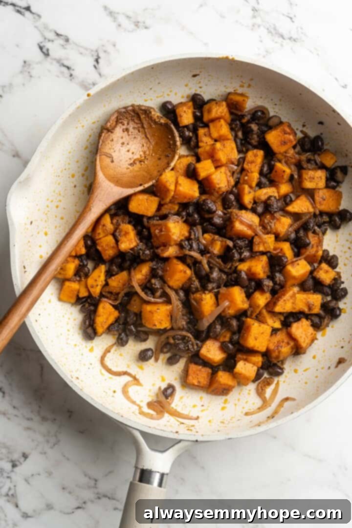 Overhead view of the sweet potato and black bean taco filling mixture cooking in a skillet, showing the vibrant colors and seasonings