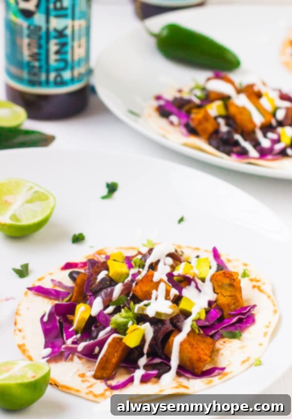 Black bean and sweet potato taco on a white plate with a wedge of lime. 