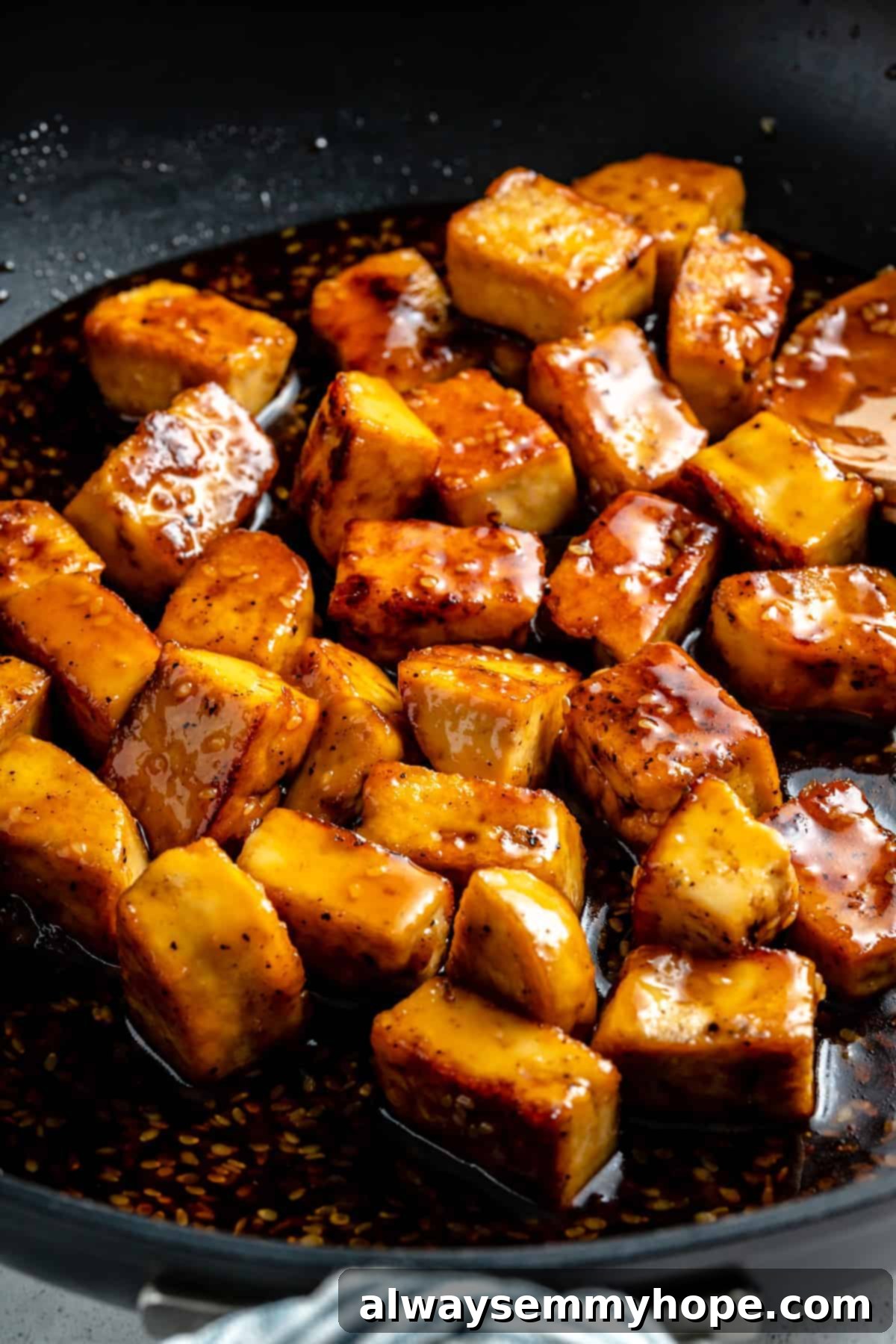 Teriyaki tofu cooking in a frying pan, with visible sauce.