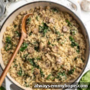 Overhead view of coconut creamy spinach and mushroom quinoa in skillet with wooden spoon