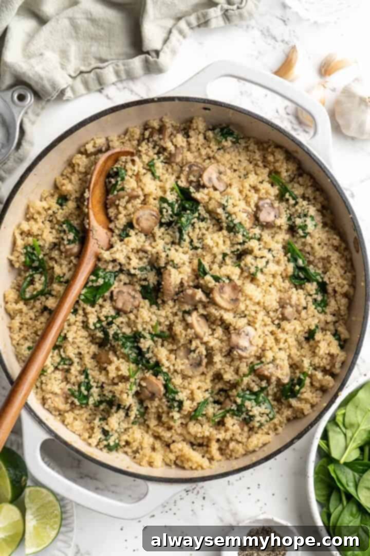 Overhead view of the finished creamy coconut spinach and mushroom quinoa in a skillet with a wooden spoon, ready to serve.