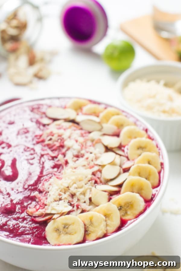 Banana berry beet smoothie bowl with sliced almonds and sliced bananas on top.
