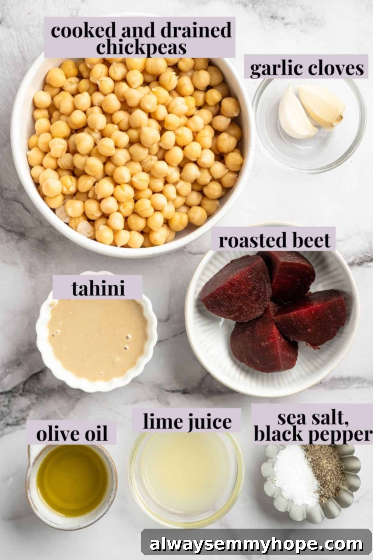 A colorful array of fresh ingredients for making homemade beet hummus, highlighting its natural and wholesome components. Overhead view of fresh ingredients for beet hummus, including roasted beets, chickpeas, lime, garlic, and tahini, neatly arranged on a white surface.