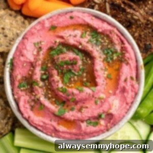 Velvety Beet Hummus 2 Bowl of vibrant pink beet hummus on a platter with assorted crudite and crackers, ready for serving.