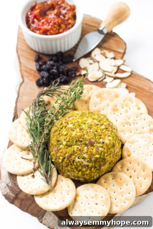 Pistachio Crowned Vegan Cheese Ball 3 Top down shot of pistachio crusted vegan cheese ball on a wooden board with crackers.