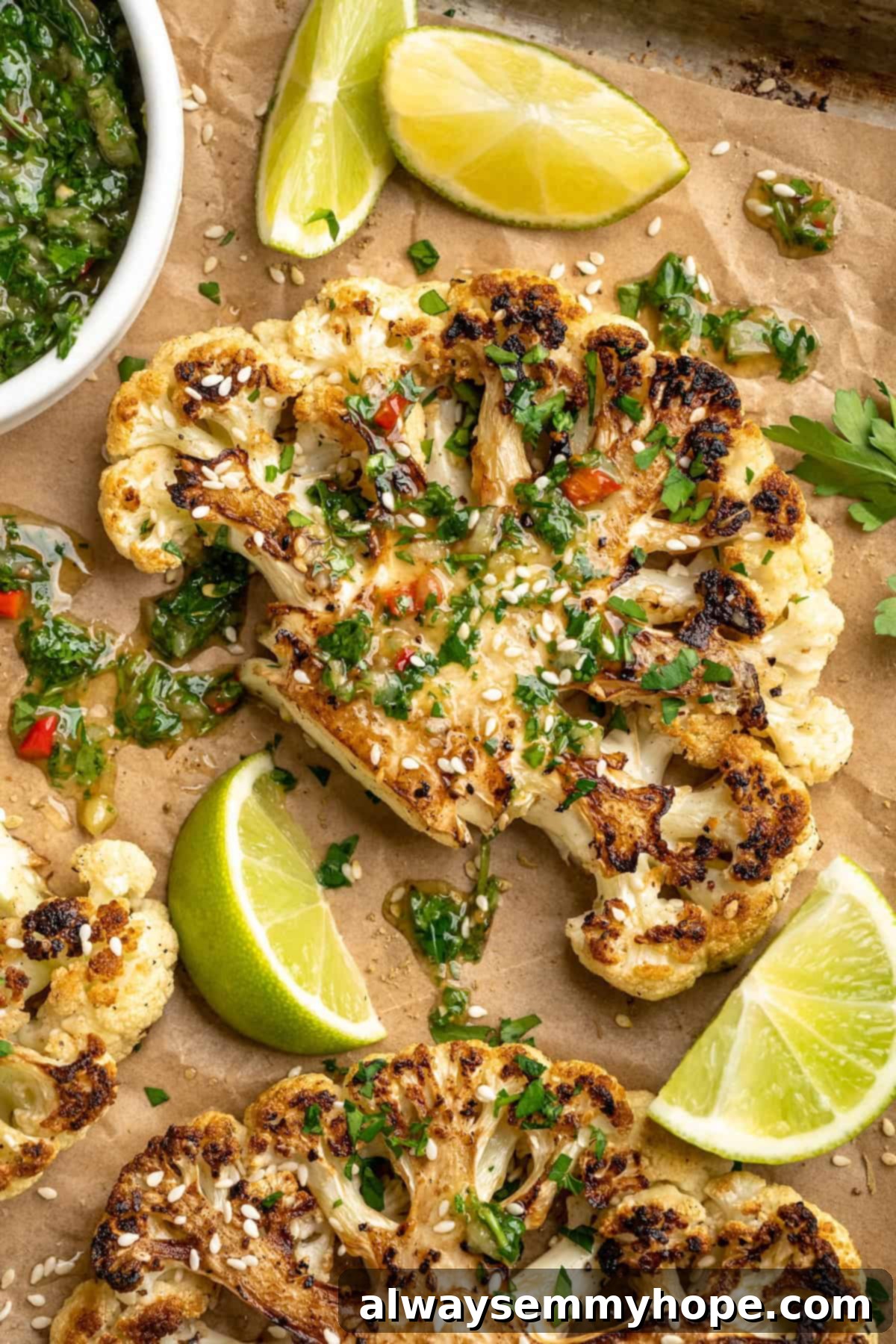 These easy roasted cauliflower steaks are tender, crispy on the edges, and incredibly flavourful thanks to the addition of za’atar! Overhead view of cauliflower steaks on sheet pan drizzled with chimichurri