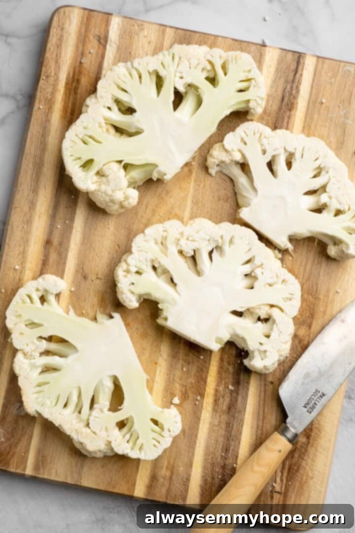 These easy roasted cauliflower steaks are tender, crispy on the edges, and incredibly flavourful thanks to the addition of za’atar! Overhead view of cauliflower steaks on cutting board with knife