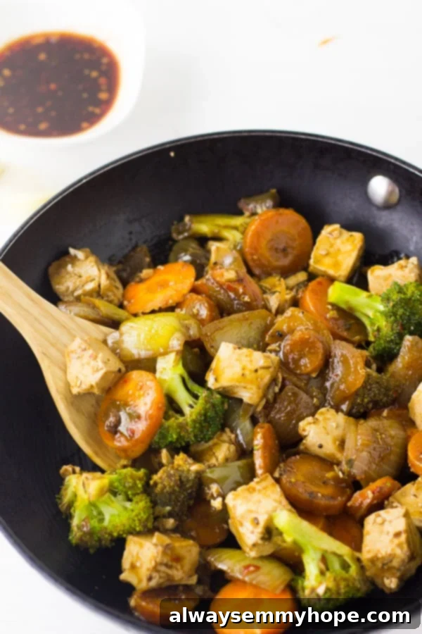April Bounty Produce Guide 3 A rich Asian tofu stir-fry brimming with colorful vegetables, including plenty of broccoli florets, served in a black skillet.