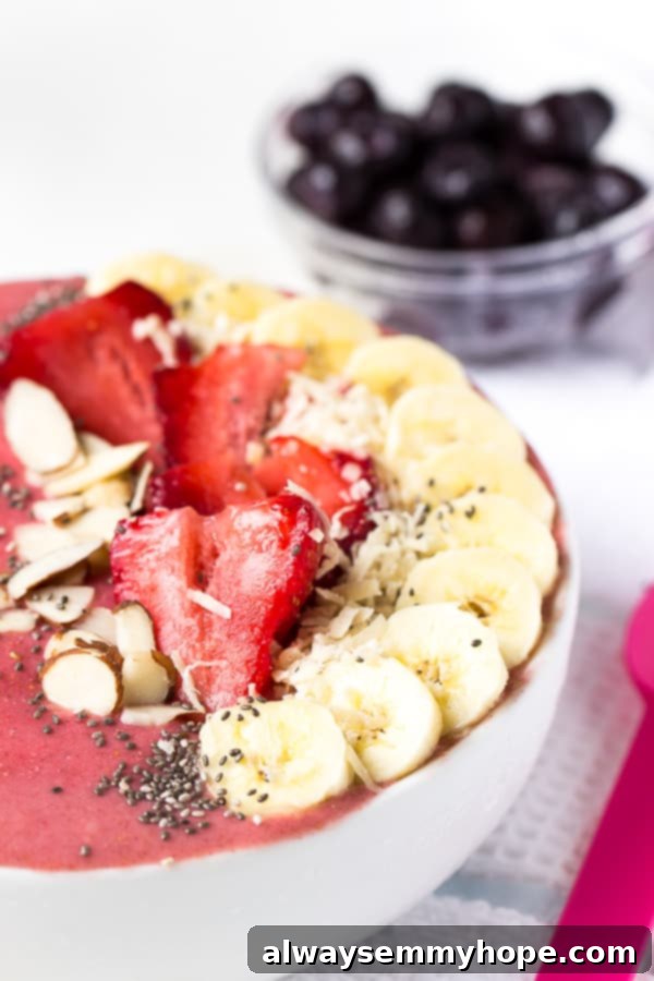 Close up of strawberry lime coconut smoothie bowl with fresh fruit on top. 
