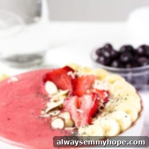 Side on shot strawberry lime coconut smoothie bowl with fresh fruit on top.