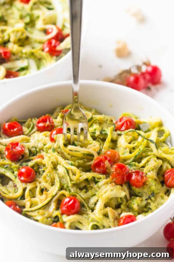 Zucchini Noodles with Pesto and Burst Cherry Tomatoes 4 Close-up shot of a fork twirling pesto zucchini noodles, emphasizing the creamy sauce and tender texture.