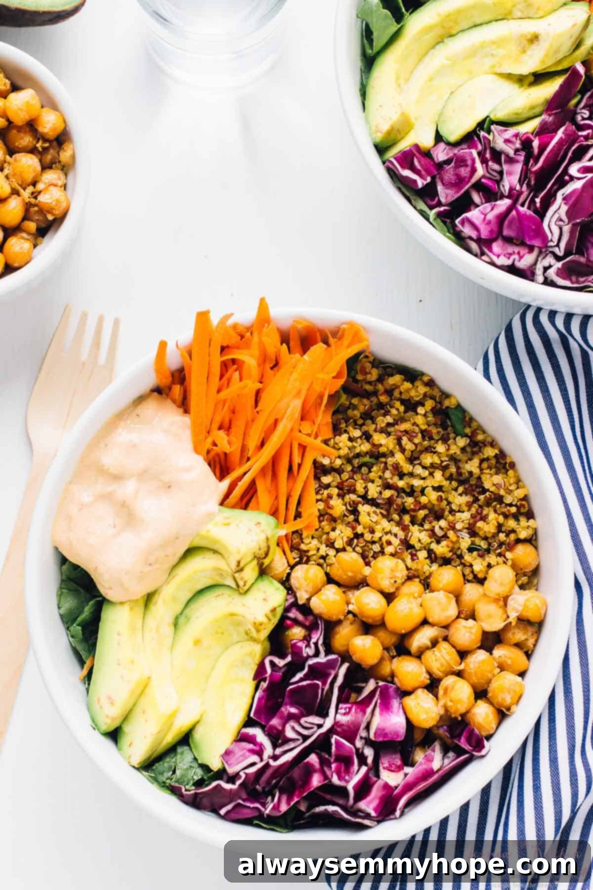 Nourishing Buddha Bowl with Harissa Tahini Dressing 2 Top down shot of nourish Buddha Bowl on a white table with a wood fork on the side.