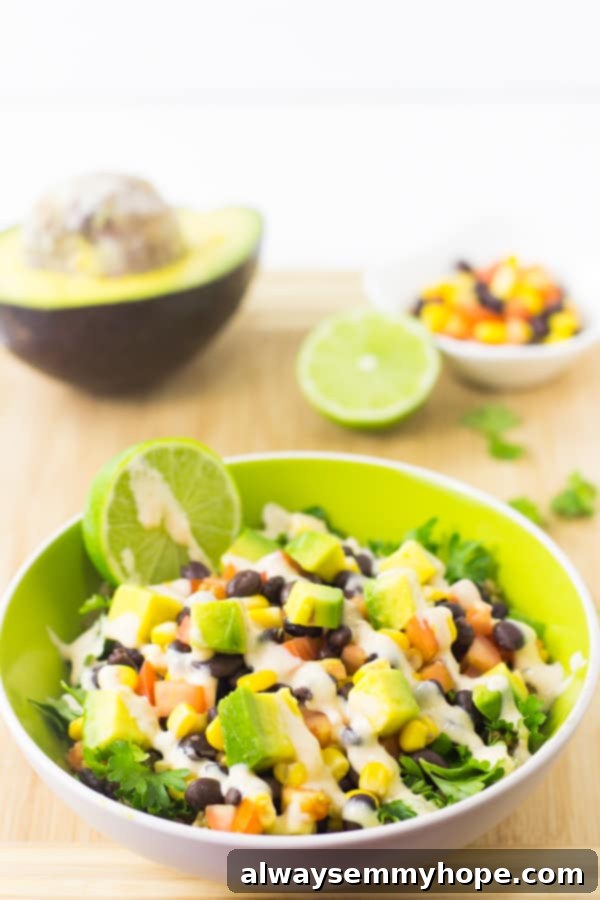 Quinoa and black bean burrito bowl on a wood table top with wedges of lime. 