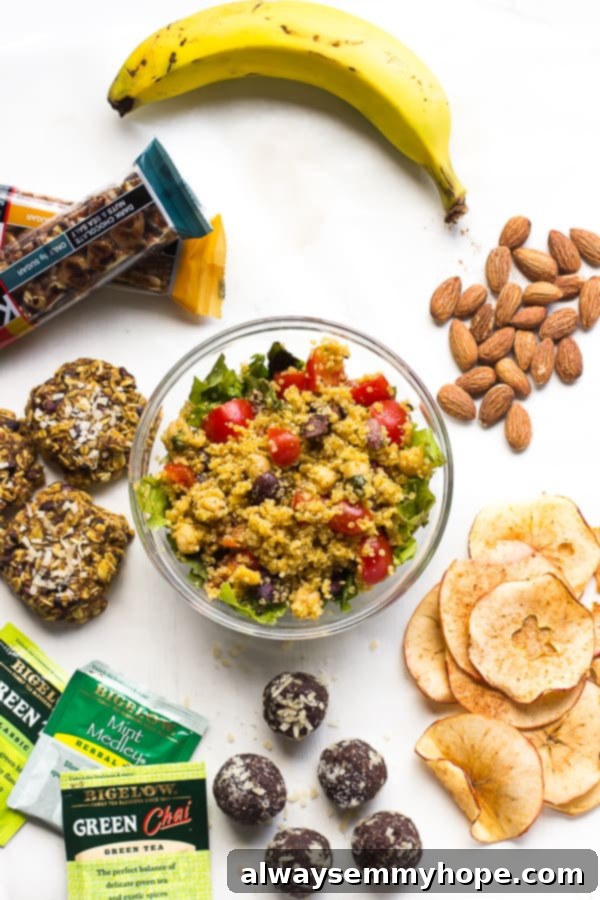 An array of delicious and healthy travel snacks, including nuts, fruit, and baked goods, neatly arranged on a white table.