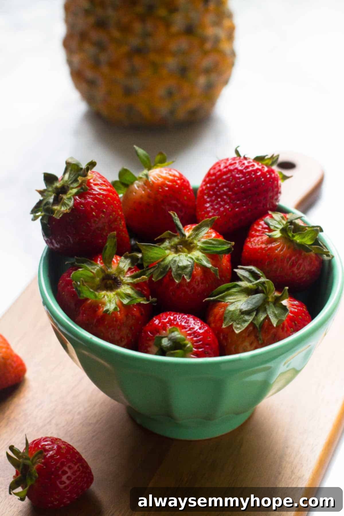 Fresh Strawberries for Lava Flow Smoothie A vibrant blue bowl brimming with fresh, ripe red strawberries, glistening and ready to be used in a delicious tropical smoothie recipe.