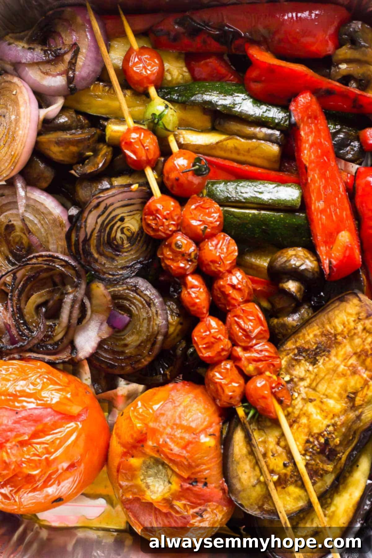 Overhead view of balsamic grilled vegetables, including cherry tomatoes on skewers, onions, zucchini, mushrooms, and eggplant