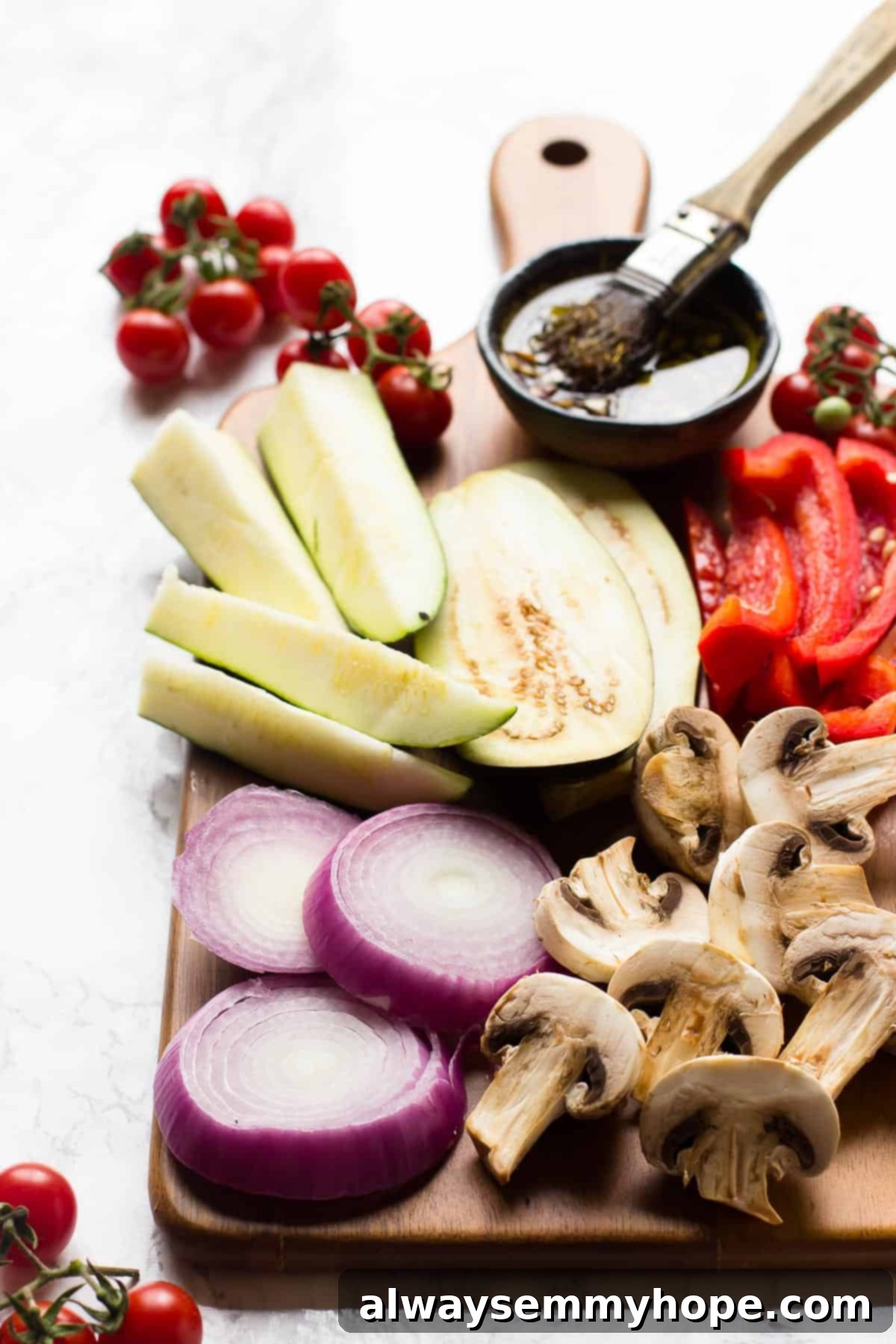 Side angle of raw veggies on a cutting board with brush and marinade