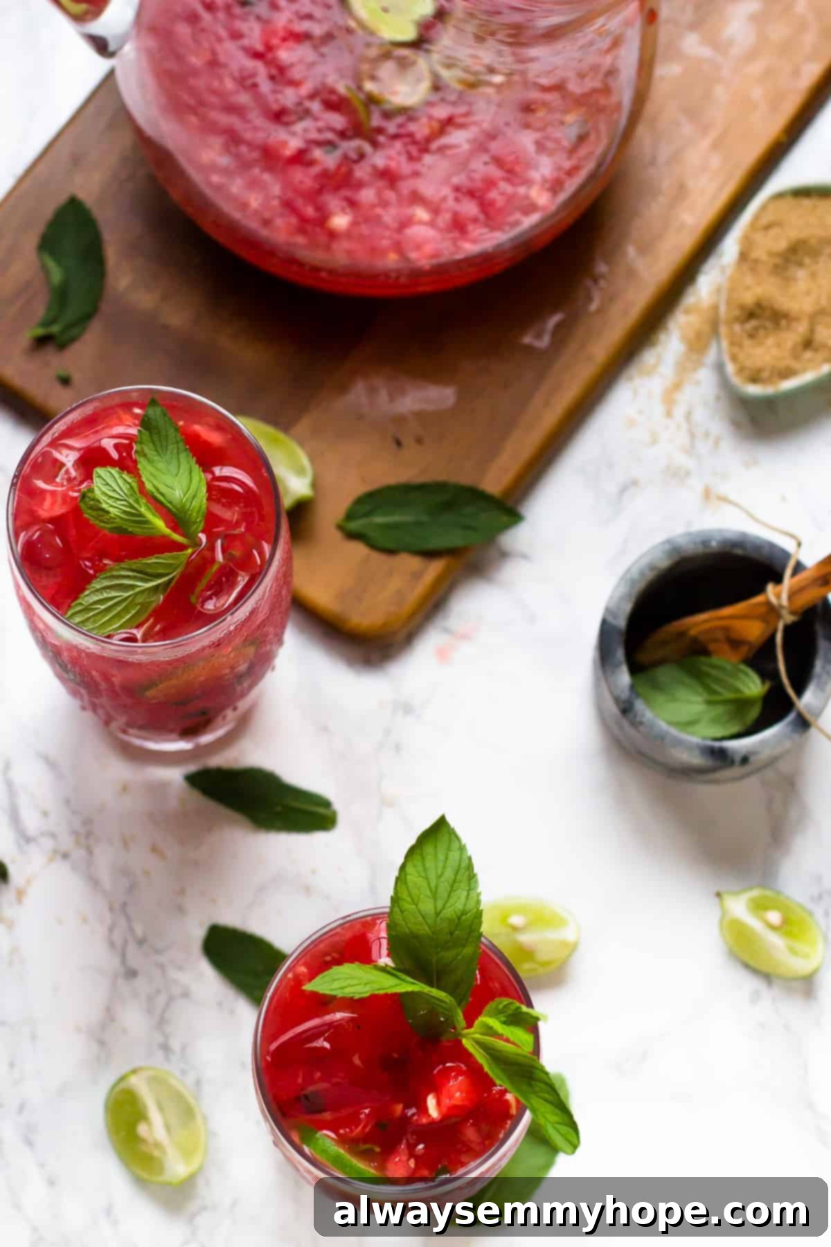 Two watermelon mojitos with pitcher on wood board