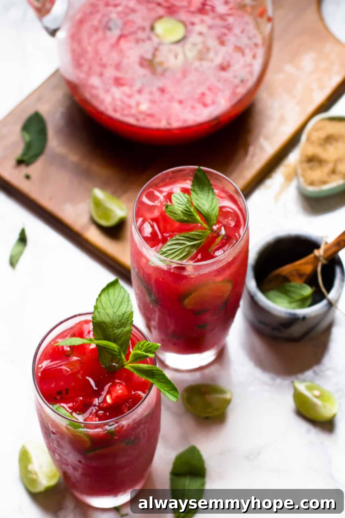 Two watermelon mojitos with pitcher on wood board