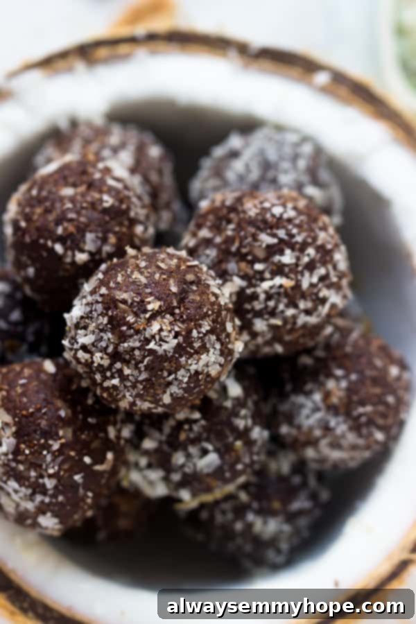 Close-up shot of several no-bake brownie energy bites piled high inside a dried coconut shell, emphasizing their texture and coconut coating.