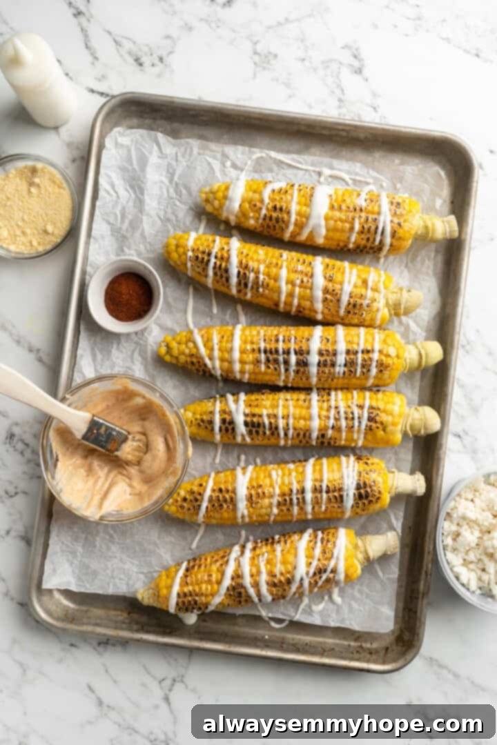 Drizzling Lime Crema on Elotes. Overhead view of Mexican street corn drizzled generously with lime crema.