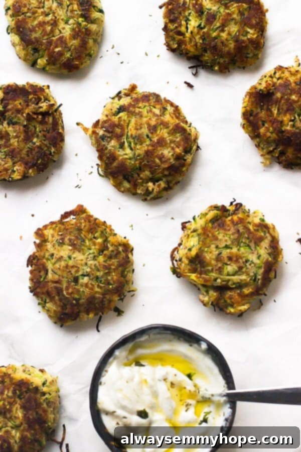 30-Minute Crispy Gluten-Free Vegan Zucchini Fritters Recipe Close-up overhead view of golden-brown gluten-free vegan zucchini fritters on a white plate with a small bowl of lime crema.