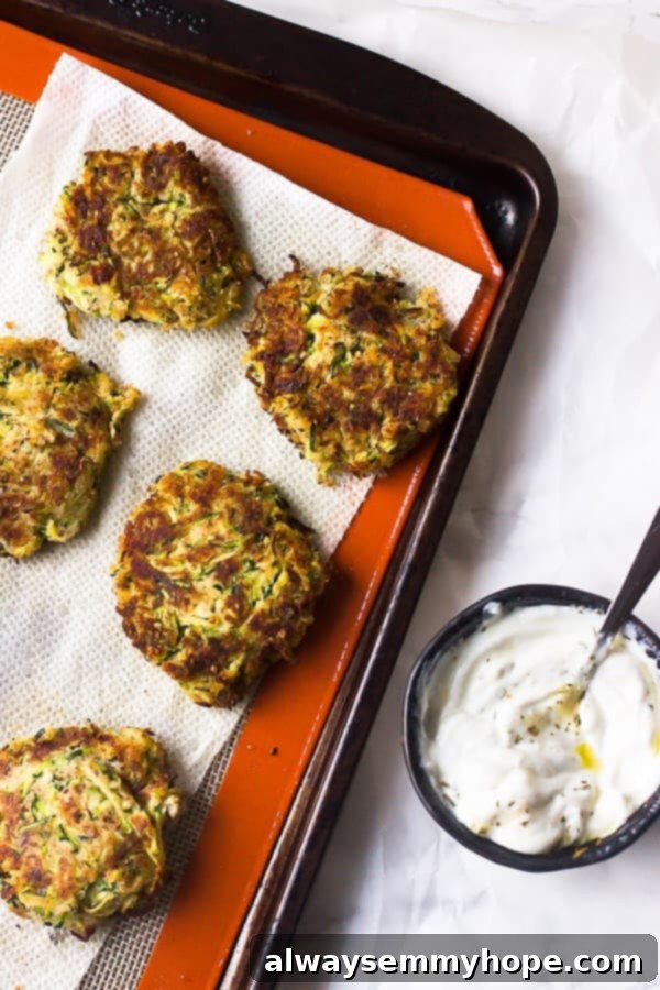 Tips for Crispy Gluten-Free Vegan Zucchini Fritters Pile of golden-brown vegan zucchini fritters resting on a paper towel-lined plate to absorb excess oil.