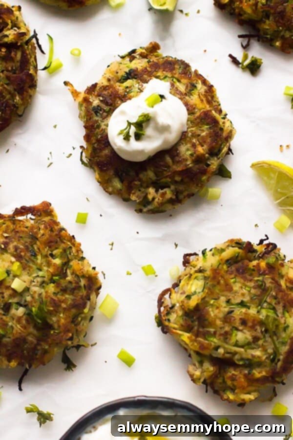 Crispy Zucchini Fritters with Creamy Sauce Close-up of a single golden-brown vegan zucchini fritter with a dollop of white sauce on top, garnished with fresh herbs.